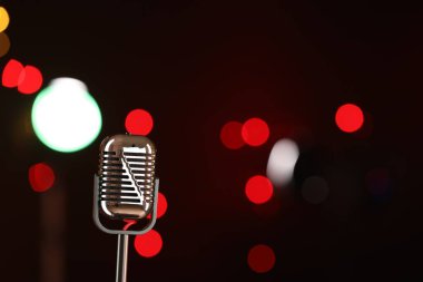 Karanlık arka planda bulanık ışıkları olan klasik mikrofon, mesaj için yer. Müzik ekipmanları