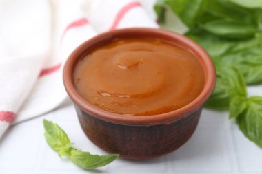 Lezzetli köri sosu ve fesleğen yaprakları beyaz fayanslı masada, yakın plan.