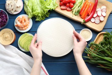 Mavi ahşap masada nefis börek yapan bir kadın.