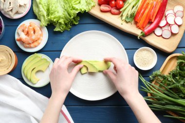 Mavi ahşap masada nefis börek yapan bir kadın.