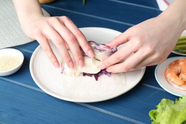 Mavi ahşap masada nefis börek yapan bir kadın, yakın plan.