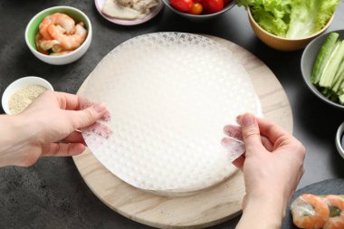 Koyu gri masada nefis börek yapan bir kadın.