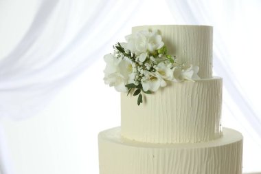 Çiçek desenli nefis düğün pastası ve beyaz arka planda perdeler, yakın plan. Metin için boşluk
