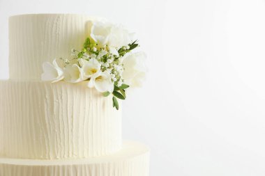 Beyaz arka planda çiçeklerle süslenmiş nefis düğün pastası, yakın plan. Metin için boşluk