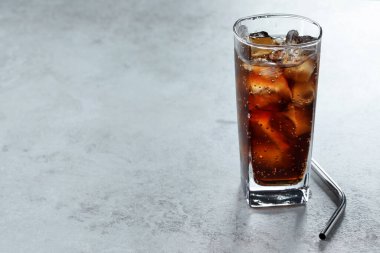 Kola, buzlu bardak ve gri desenli masada saman ile tazeleniyor. Yakın plan. Metin için boşluk