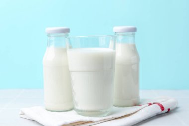 Açık mavi arka planda beyaz masada taze süt