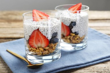 Chia tohumlu lezzetli tatlı, yoğurt, granola, çilek ve böğürtlen ahşap masada, yakın plan. Süper yemek.