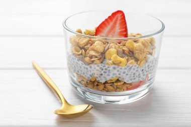 Chia tohumlu lezzetli tatlı, yoğurt, granola ve beyaz ahşap masadaki çilekler, yakın plan. Süper yemek.