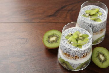 Süper yemek. Chia tohumlu lezzetli tatlı, yoğurt, tahıl gevreği ve ahşap masada kivi, yakın plan. Metin için boşluk