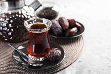 Geleneksel Türk çayı cam fincanda, çaydanlıkta ve açık gri masada, yakın plan. Metin için boşluk