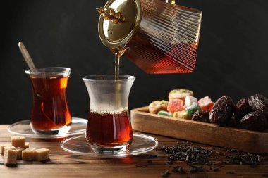 Tahta masada cam fincana Türk çayı dökülüyor, yakın plan.