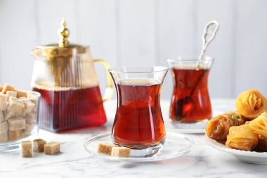 Lezzetli Türk çayı, beyaz mermer masada şekerlerle servis edilir.