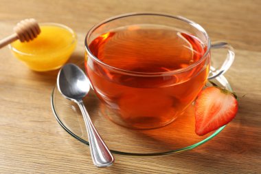 Çilekli ve ballı Aromatik meyve çayı, ahşap masa, yakın plan.