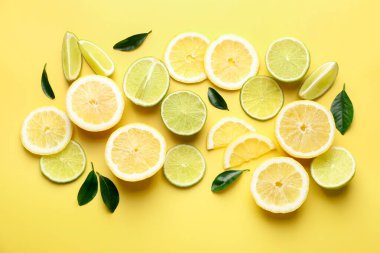 Sarı arka planda limon ve limon dilimleri, düz uzanmış.