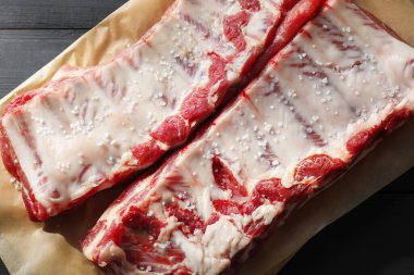 Siyah ahşap masada deniz tuzu ve çiğ domuz pirzolası.