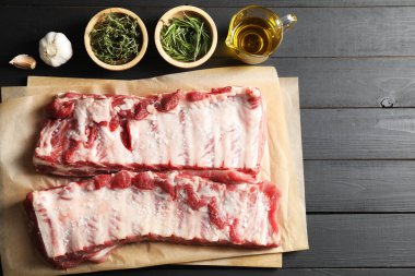 Çiğ domuz pirzolası, deniz tuzu, yağ, sarımsak ve otlar siyah ahşap masa üzerinde, düz yatıyordu.