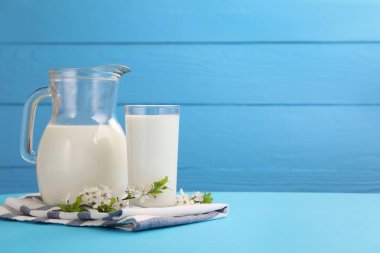 Açık mavi masada taze süt ve çiçekler var. Metin için boşluk