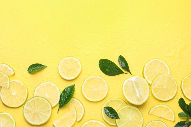 Dilimler taze limon ve yeşil yapraklar sarı arka planda, düz yerde. Metin için boşluk