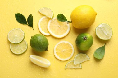 Taze limon, limon ve yeşil yapraklar sarı arka planda, düz yerde
