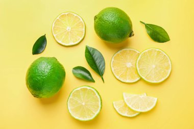 Taze limon ve yeşil yapraklar sarı arka planda, düz yatıyordu.