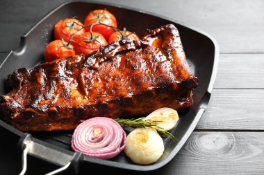 Biberiyeli domuz pirzolası, domates ve soğan. Gri ahşap masada, yakın plan.