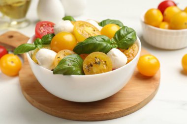Taze salata, sarı domates, fesleğen ve mozzarella peyniri beyaz masada, yakın plan.