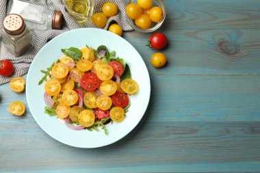 Açık mavi ahşap masada servis edilen yeşil domatesli taze salata. Metin için boşluk