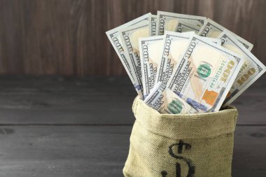 Gri ahşap masanın üzerinde dolar banknotları olan para çantası, yakın plan. Metin için boşluk