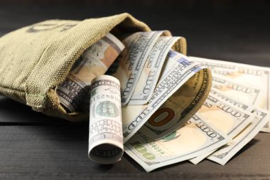Üzerinde dolar banknotları olan para çantası. Gri ahşap masa, yakın plan.