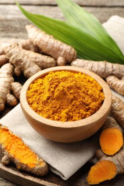 Tabaktaki zerdeçal tozu, kökler ve yapraklar masada, yakın plan.