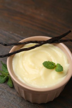 Lezzetli vanilyalı puding, nane ve kapsüller ahşap masada, yakın plan.