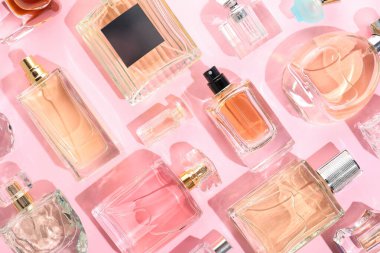 Pembe arka planda çeşitli parfüm şişeleri, düzlük