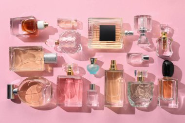 Pembe arka planda çeşitli parfüm şişeleri, düzlük