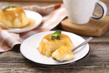 Karamel soslu lezzetli puding ve ahşap masada servis edilen nane.