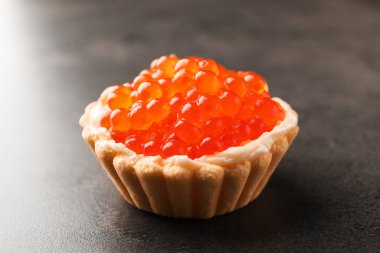 Gri masadaki kırmızı havyarlı lezzetli kanepe, yakın plan.