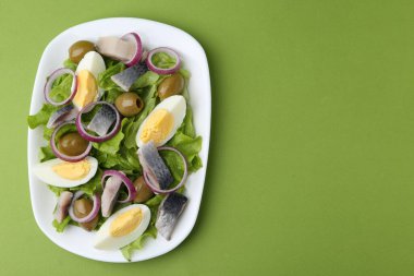 Ringa balıklı lezzetli salata, yeşil arka planda yumurta ve sebzeler, üst manzara. Metin için boşluk