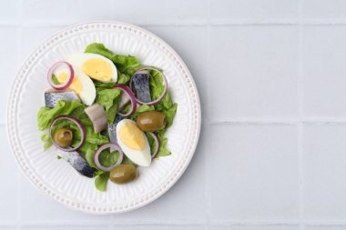 Ringa balıklı nefis salata, yumurta ve sebzeler beyaz fayanslı masa, üst manzara. Metin için boşluk
