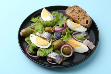 Açık mavi arka planda ringa balıklı, yumurtalı, hardallı ve sebzeli lezzetli salata.