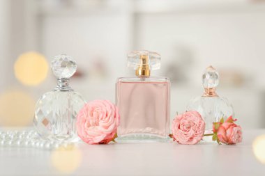 Parfüm şişeleri ve beyaz masada güzel çiçekler.