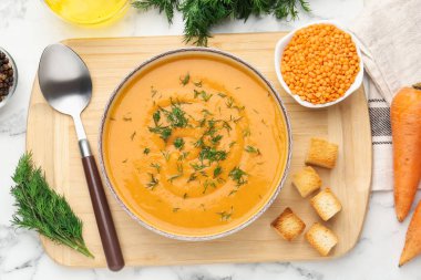 Lezzetli mercimek kremalı çorba, bembeyaz mermer masa üzerinde malzemeler, düz uzanmış.