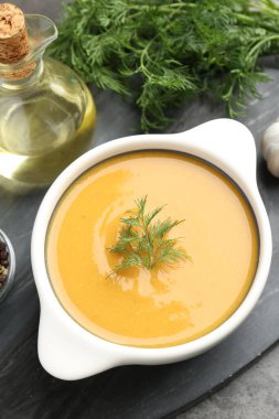 Gri masada servis edilen dereotlu mercimek kremalı çorba.