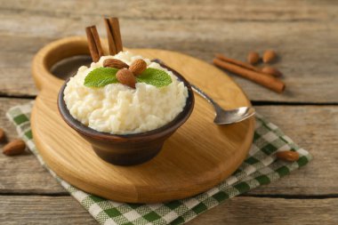 Tahta masada servis edilen bademli, nane ve tarçınlı lezzetli sütlaç, yakın plan.