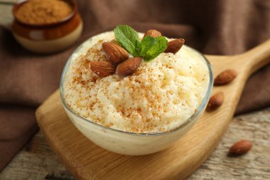 Tarçınlı lezzetli pirinç pudingi, ahşap masada nane ve badem, yakın plan.