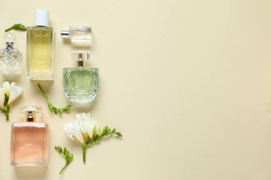 Parfüm şişeleri ve bej arka planda güzel çiçekler. Metin için boşluk