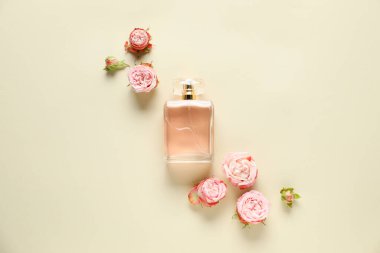 Bir şişe parfüm ve bej arka planda güzel çiçekler.