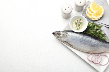 Tuzlu ringa balığı ve baharatlar beyaz masada, düz yerde. Metin için boşluk