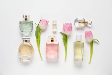 Aromatik parfüm şişeleri ve beyaz arka planda güzel laleler.