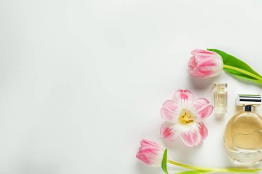 Kokulu parfüm şişeleri ve beyaz arka planda güzel çiçekler. Metin için boşluk