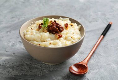 Cevizli lezzetli sütlaç, nane ve kaşık gri masada, yakın plan.