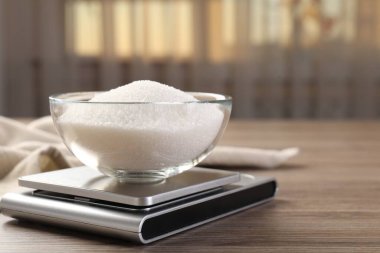 Dijital mutfak terazisi, içinde bir kase şeker olan kapalı masa, yakın plan. Metin için boşluk